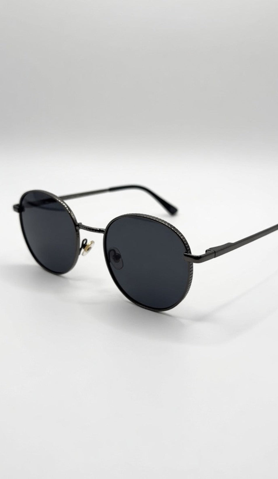 Round sunglasses with dark lenses on a light gray background